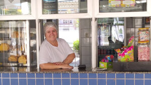 Mulher branca sorridente apoiada num balcão