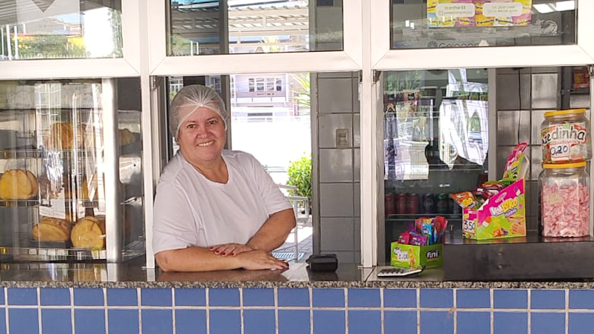 Mulher branca sorridente apoiada num balcão